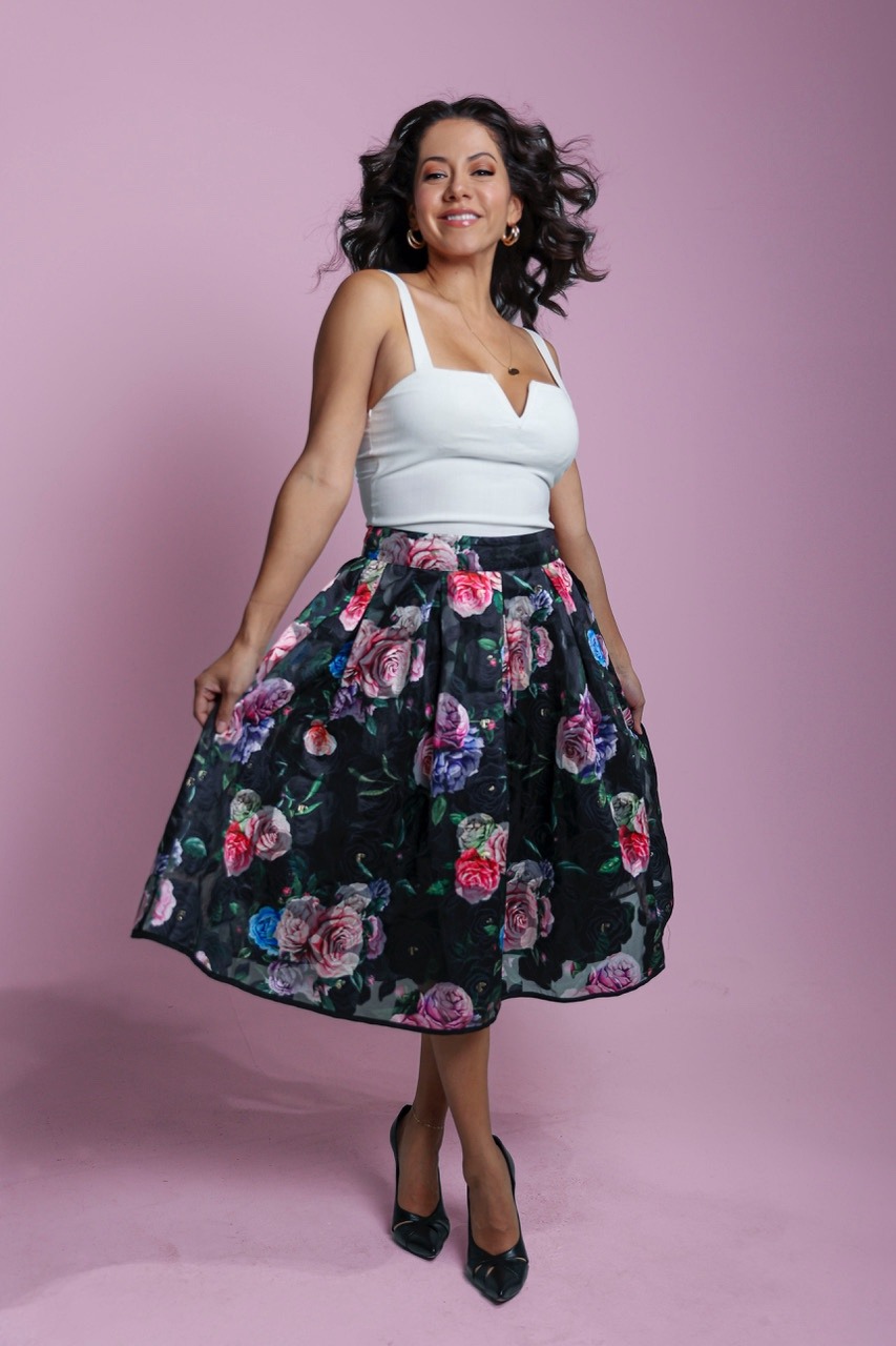 Priscilla Brehme in a floral skirt against a pink backdrop